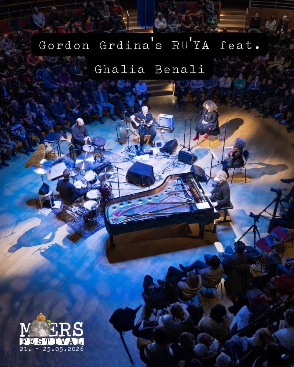 Musicians on stage, photographed from a bird's-eye view. Above them is their band name "Gordon Grdina's RU'YA feat. Ghalia Benali". The Moers Festival logo is in the bottom left corner.